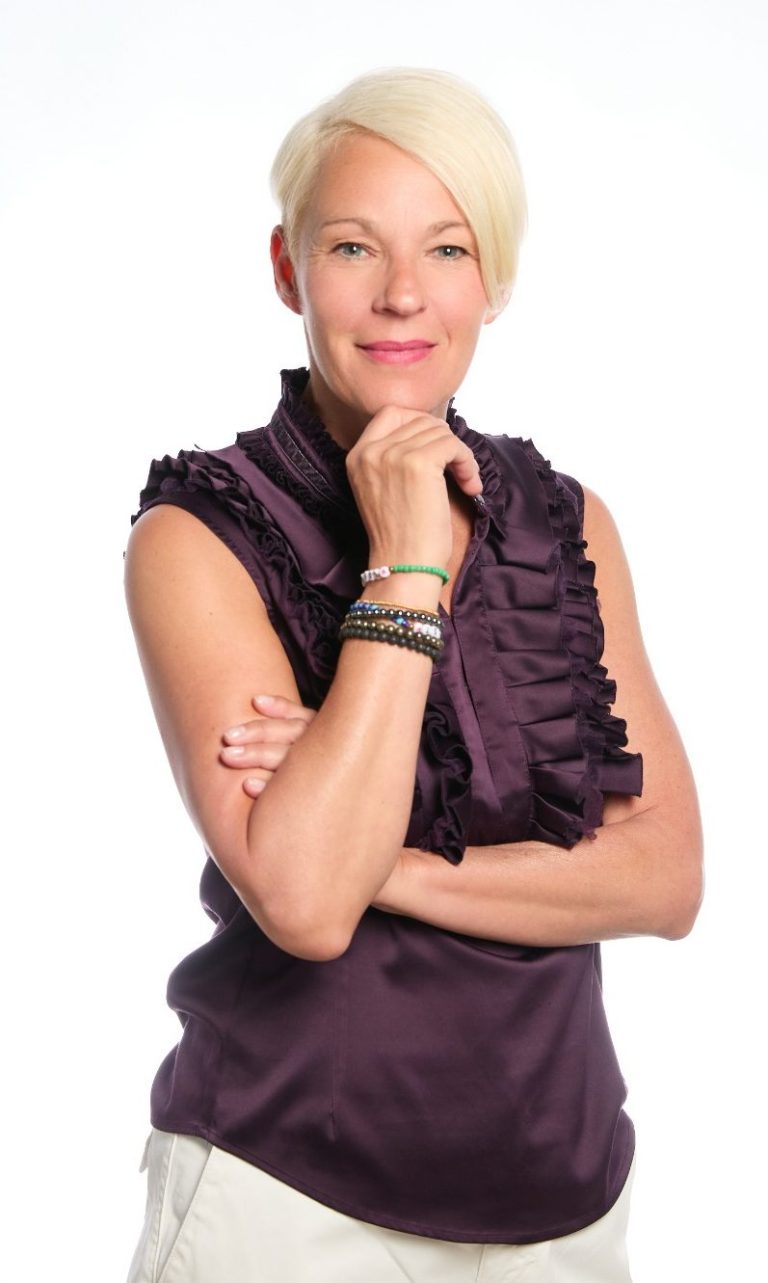 Nadja Hummer schaut mit offenem Blick in die Kamera. Sie ist dem Betrachter zugewandt und hält eine Hand unter ihr Kinn. 